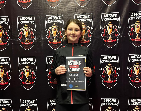 Student holding her black belt graduation certificate at Astons Kickboxing Academy, Shrewsbury