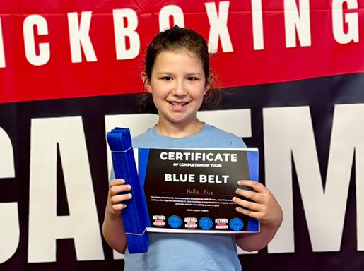 Student with her blue belt and certificate at Astons Kickboxing Academy, Shrewsbury