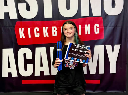 Student with her blue stripe belt and certificate at Astons Kickboxing Academy, Shrewsbury