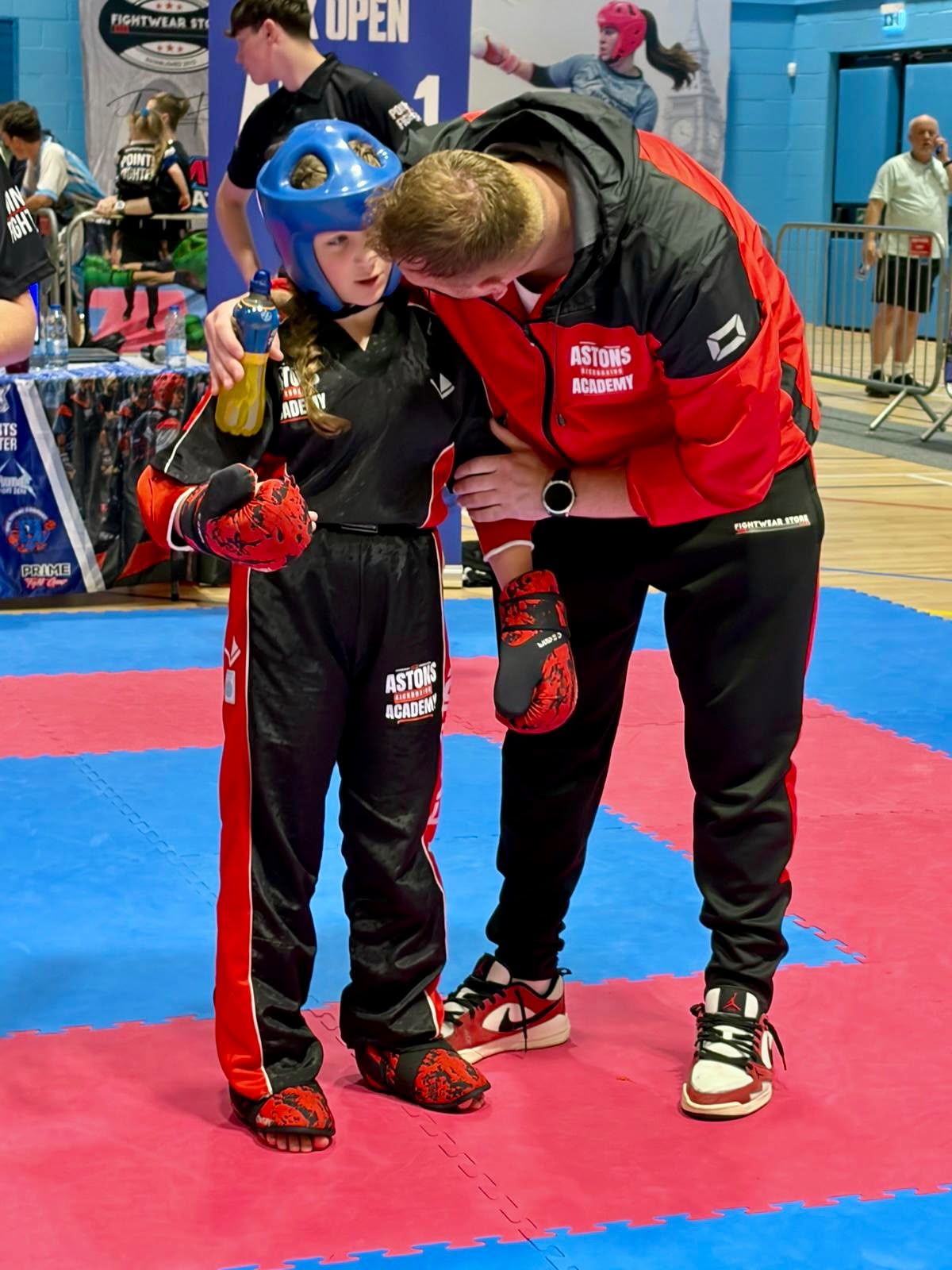 Chris Aston coaching a young fighter between rounds at a competition