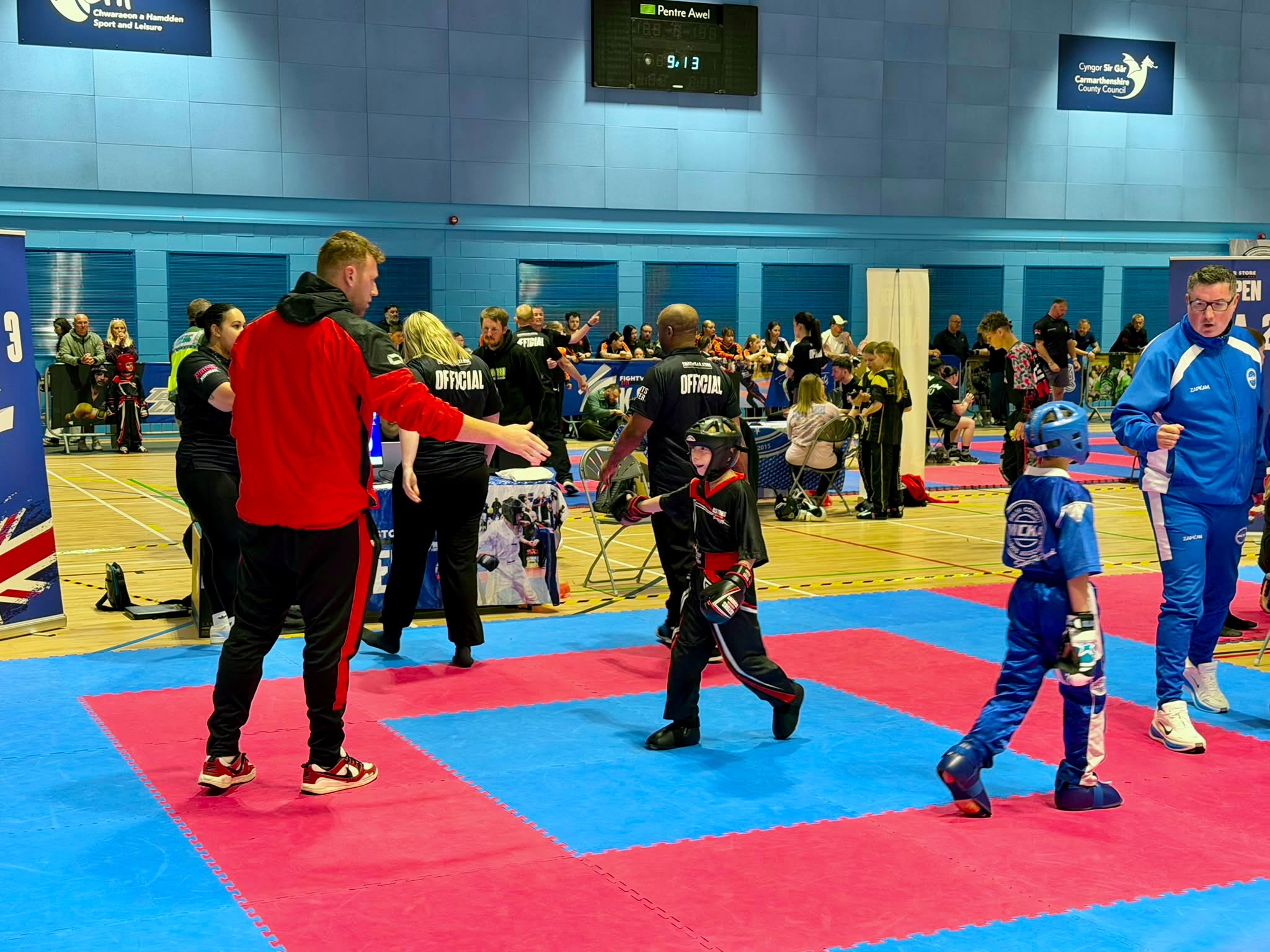 Chris Aston coaching a young Astons fighter on the mats at a kickboxing competition