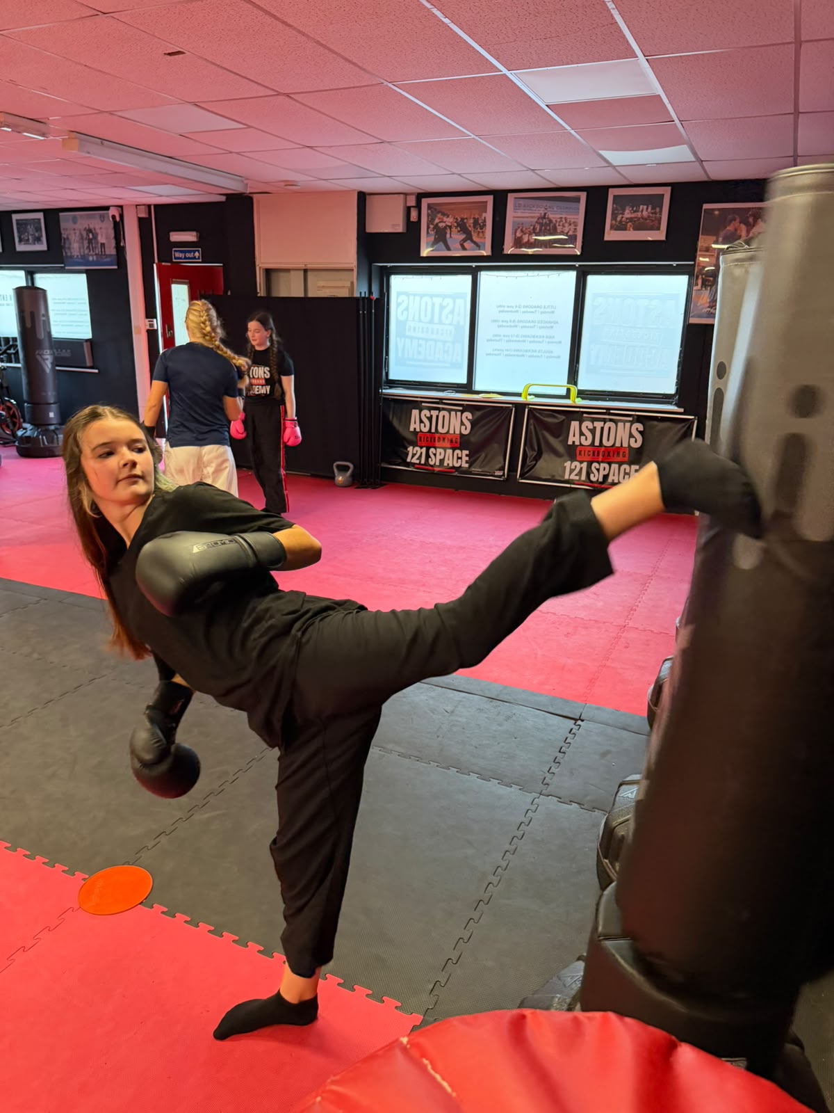 Girl kicking a punching bag in kickboxing class at Astons Kickboxing Academy, Shrewsbury