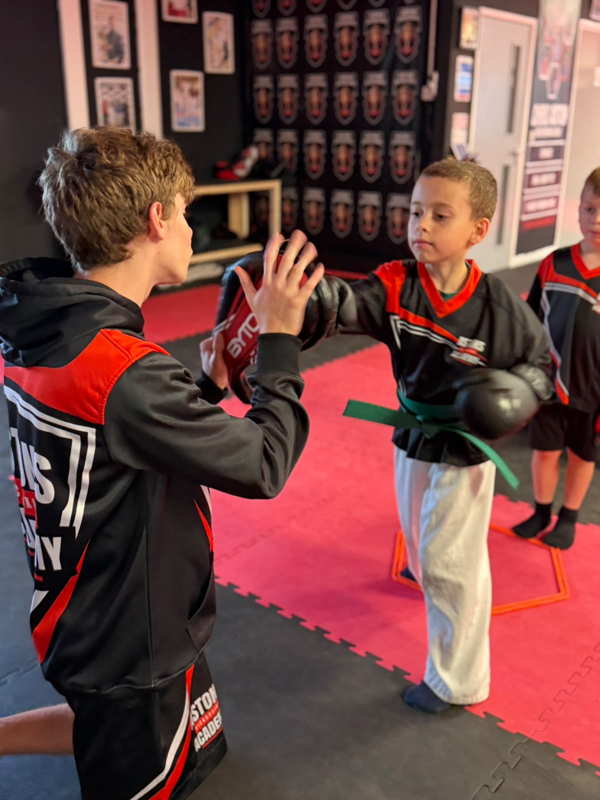 Green belt student punching a pad held by a coach at Astons Kickboxing Academy, Shrewsbury