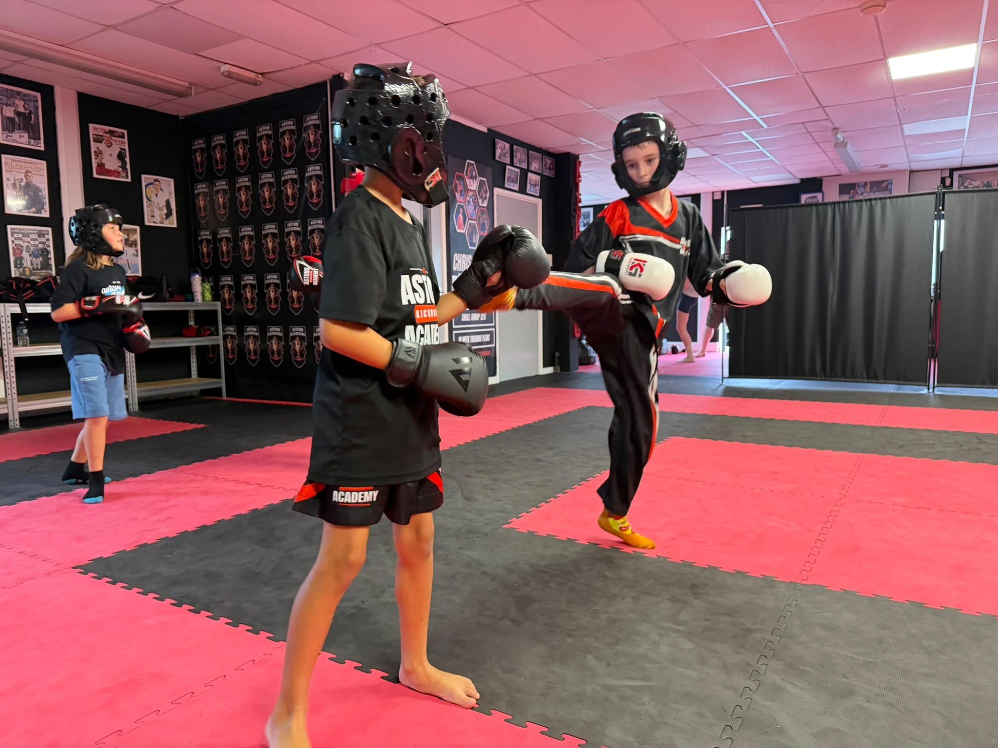 Two boys sparring in headguards and gloves in kids kickboxing class at Astons Kickboxing Academy, Shrewsbury