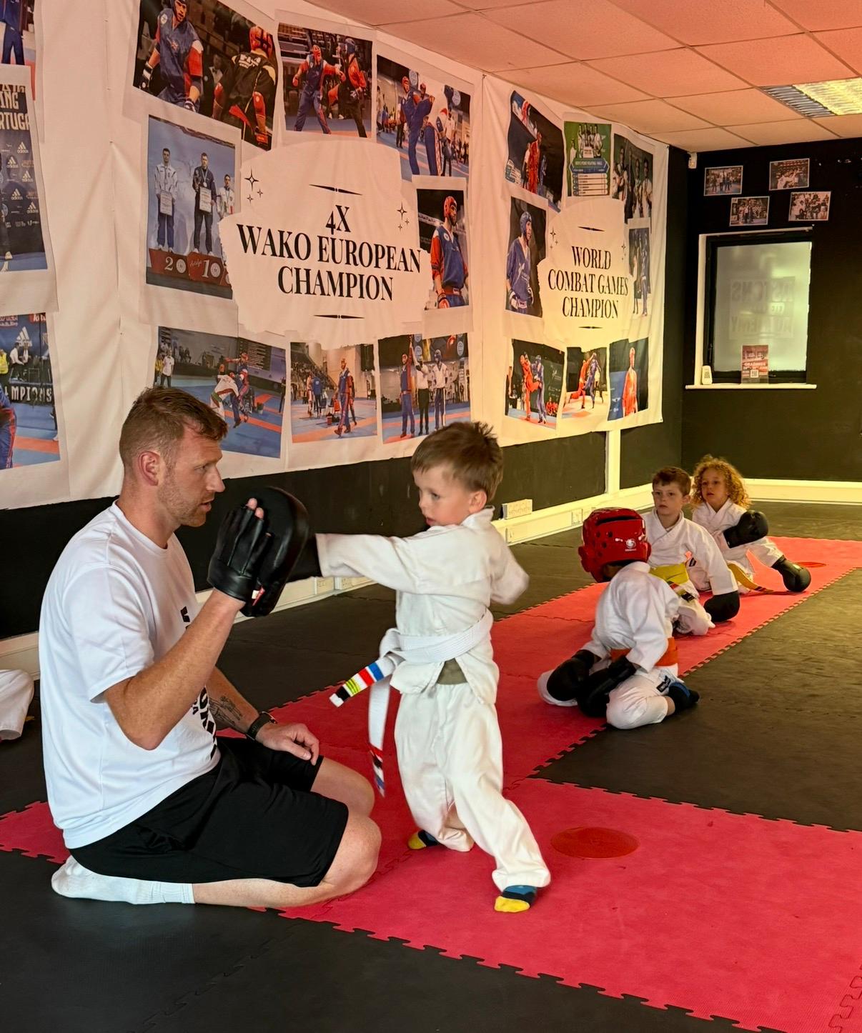 Coach holding a pad for a Little Dragons student aged 4 to 7 at Astons Kickboxing Academy, Shrewsbury