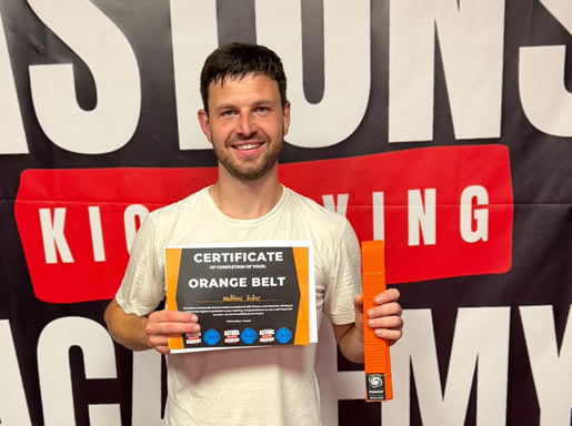 Student with his orange belt and certificate at Astons Kickboxing Academy, Shrewsbury