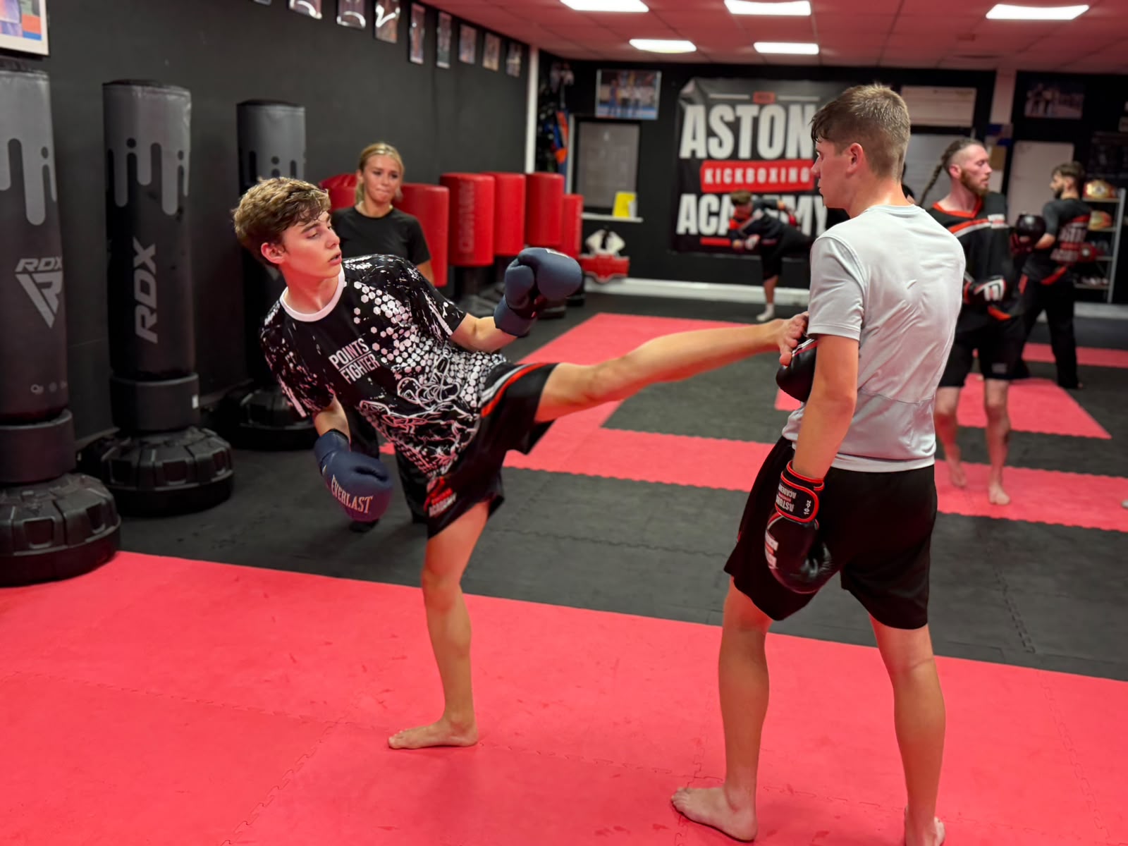 Teenager landing a high kick on the pads in a Pads and Bags class at Astons Kickboxing Academy, Shrewsbury