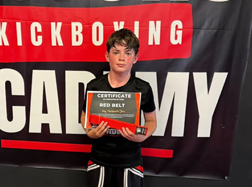 Student with his red belt and certificate at Astons Kickboxing Academy, Shrewsbury