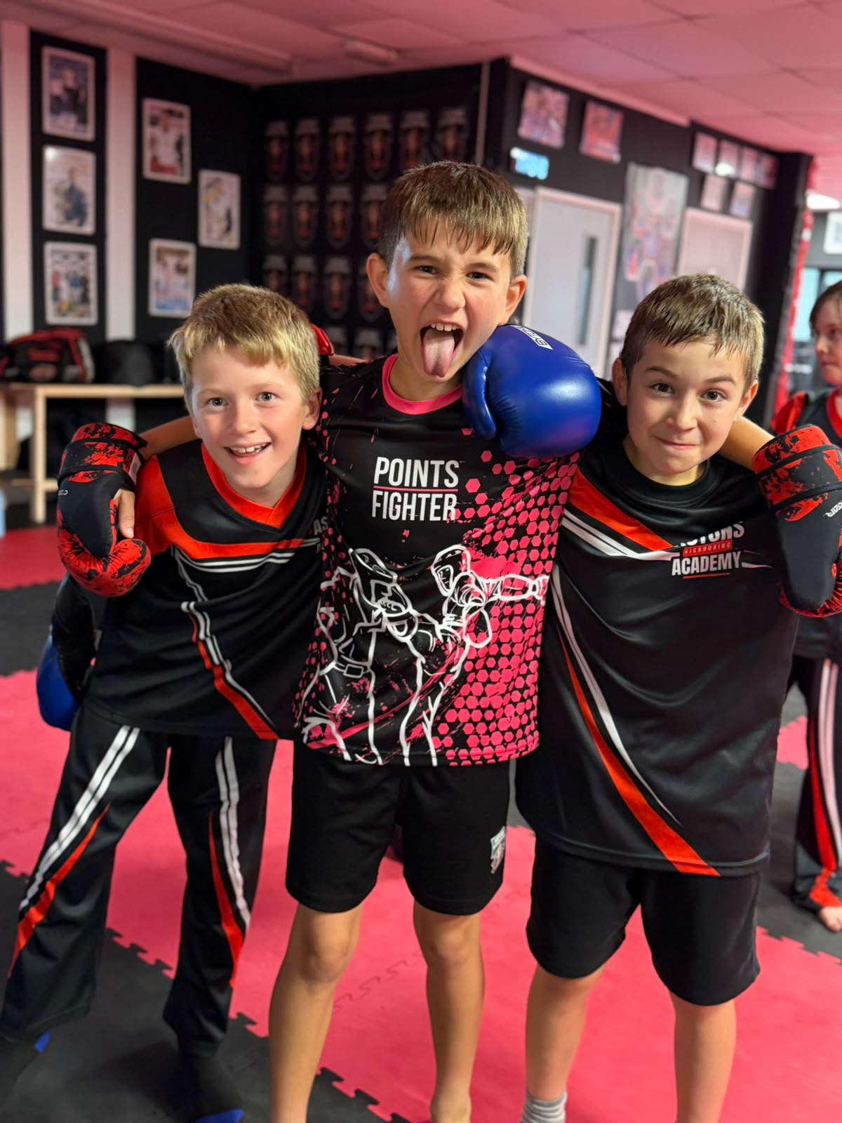 Three friends arm in arm after kids kickboxing class at Astons Kickboxing Academy, Shrewsbury